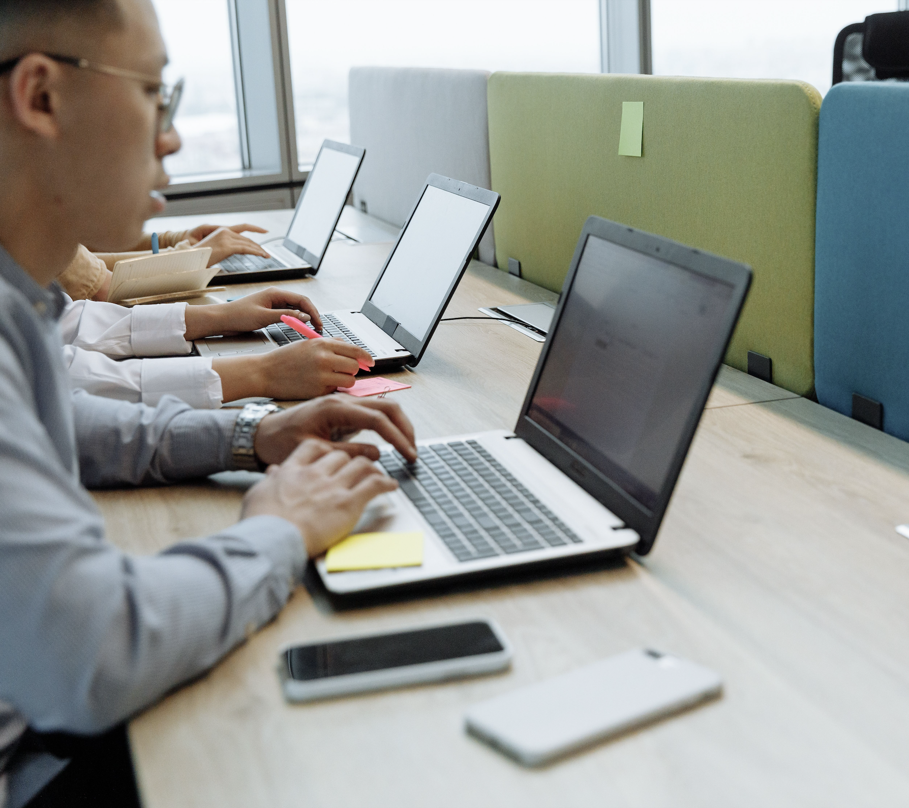 A row of employees typing on laptops at a shared desk