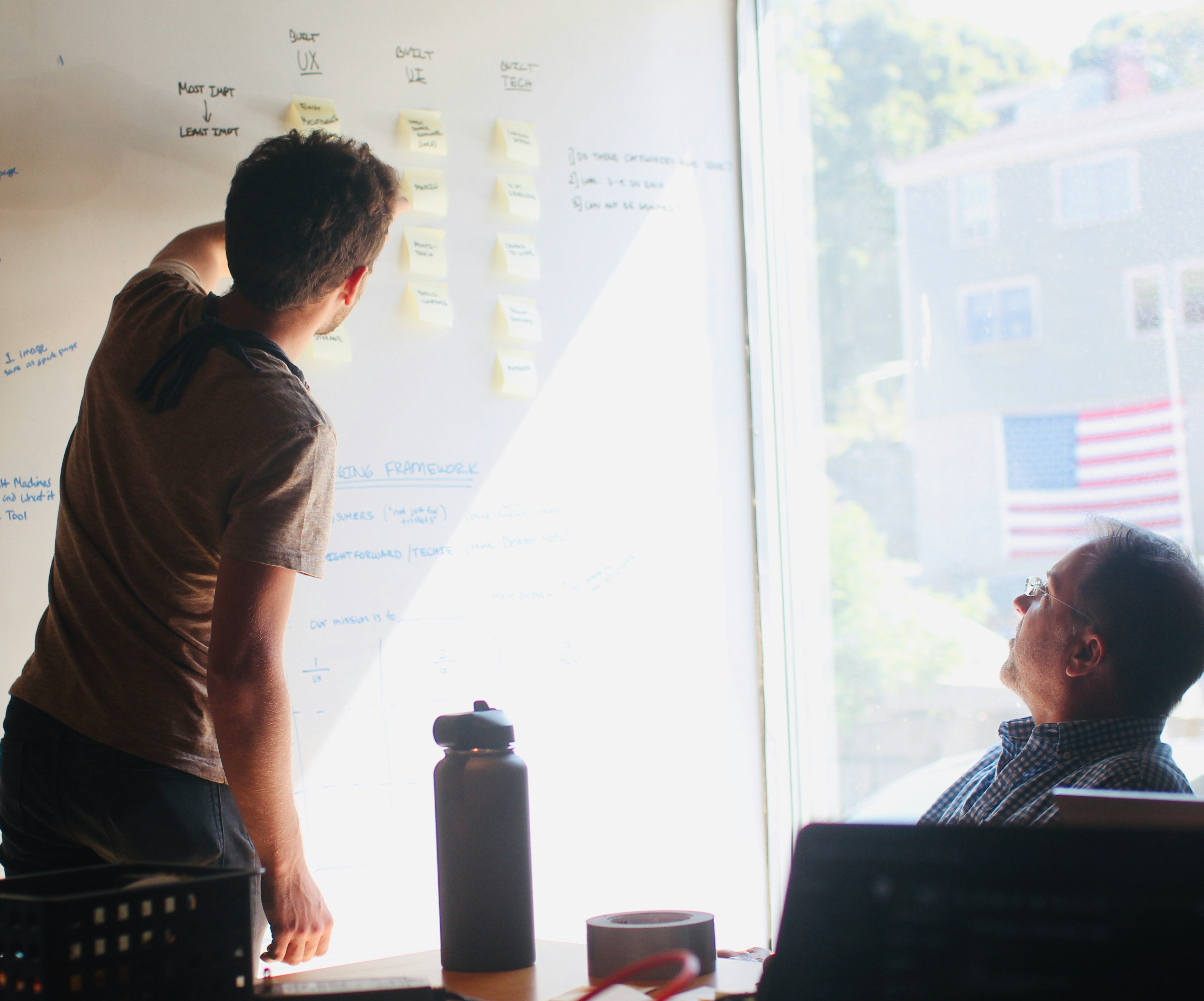 Two colleagues reviewing a whiteboard planning framework in an office
